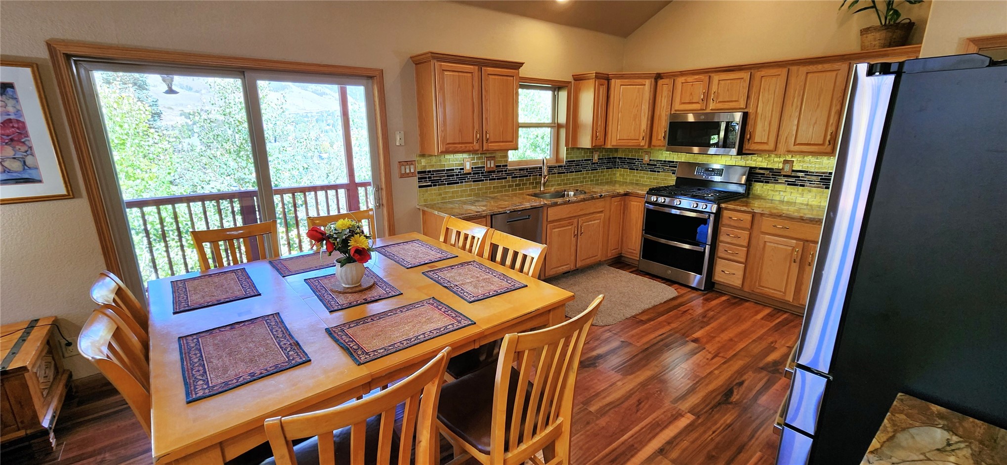 The kitchen with solid oak cabinetry, granite counters, a stainless GE Profile gas range, and a dining table set beside the deck windows