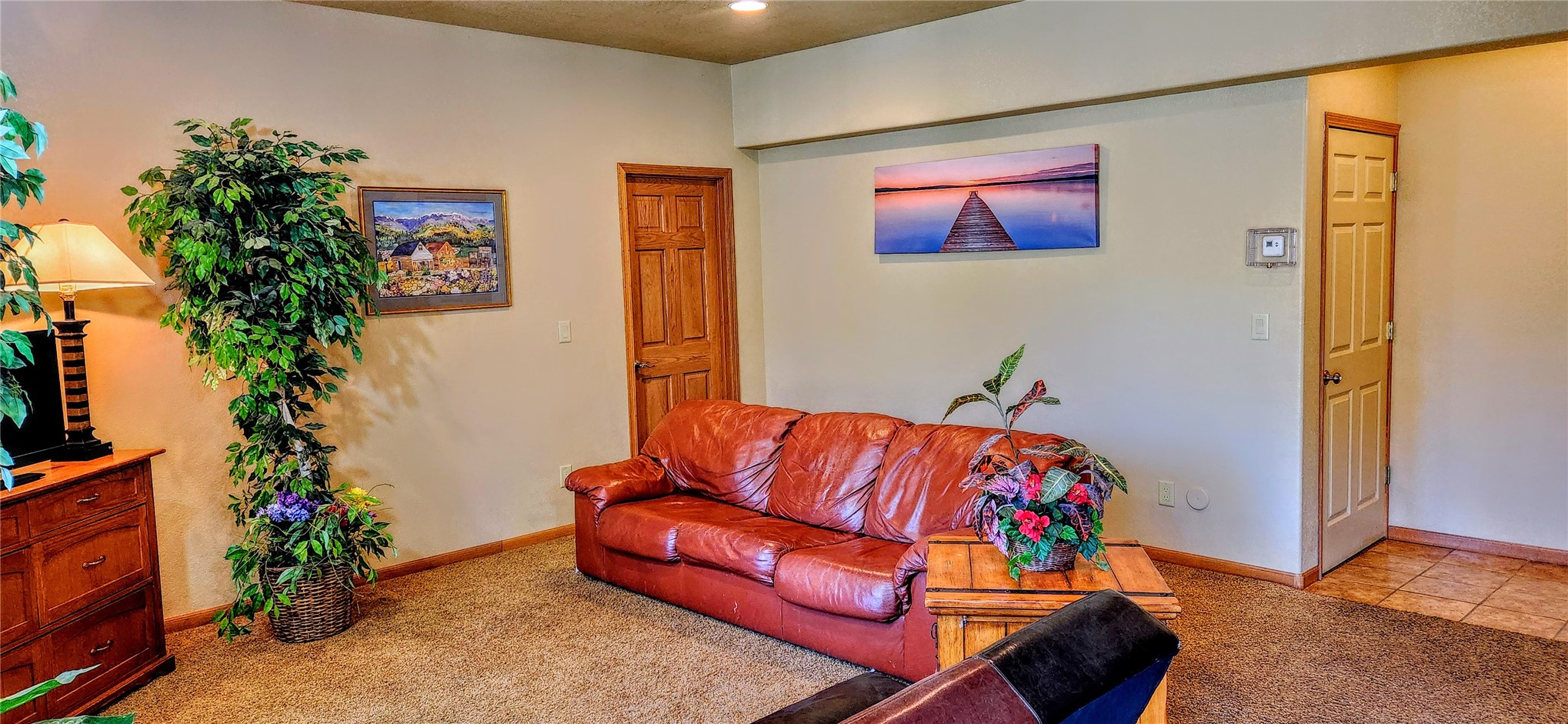 A second living area with a leather sofa, neutral carpet, oak doors, and framed art, part of the deeded accessory apartment